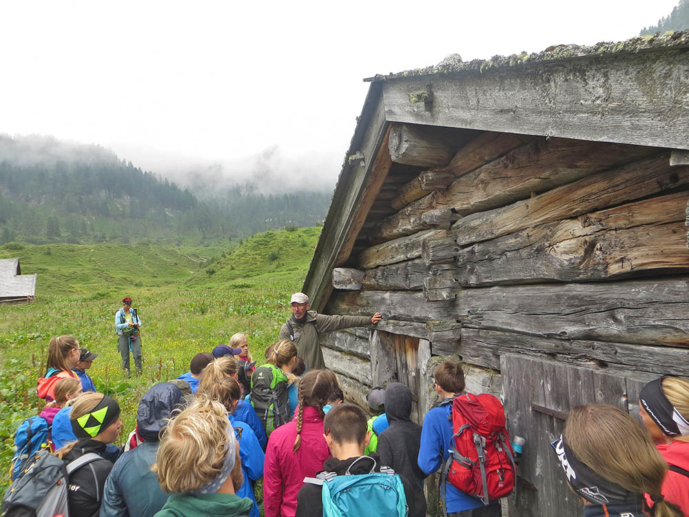 Jugendliche mit Ranger vor einer Alm-Hütte